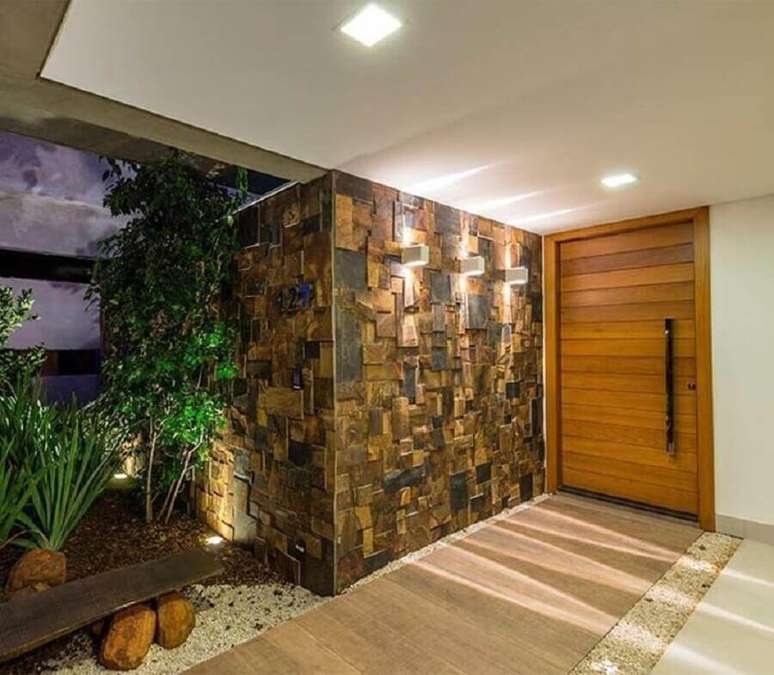 27. Entrada de casa com porta de madeira e revestimento pedra ferro em cubos – Foto: URBEM Arquitetura Ltda
