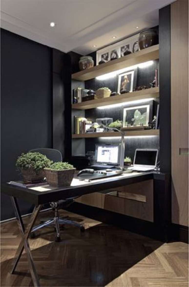 22. Escrivaninha preta em formato l. Sua estrutura está apoiada na estante de três andares com iluminação embutida. Fonte: Pinterest