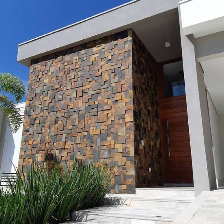 38. Pedra ferro fachada moderna com porta de madeira – Foto: Decor Salteado