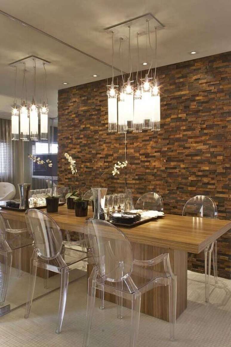 42. Pedra ferro para decoração de sala de jantar moderna com cadeiras de acrílico transparente e luminária transparente – Foto: Shopping das Pedras