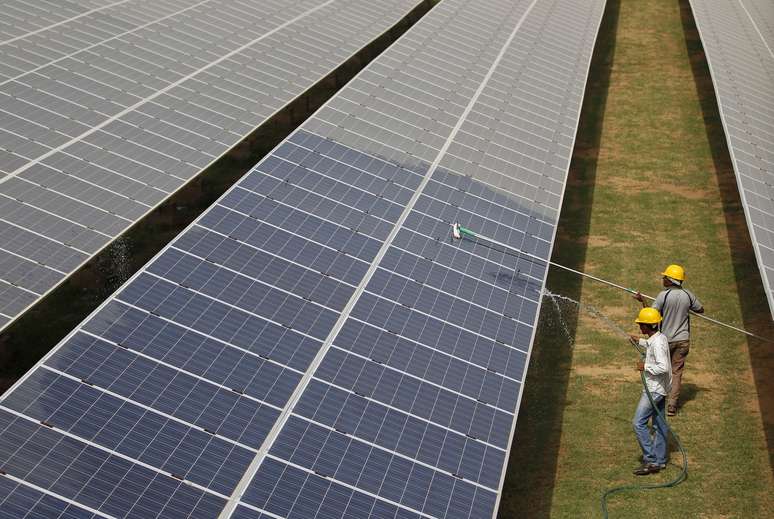 Oper&aacute;rios limpam paineis de energia fotovoltaica. 2/7/2015. REUTERS/Amit Dave