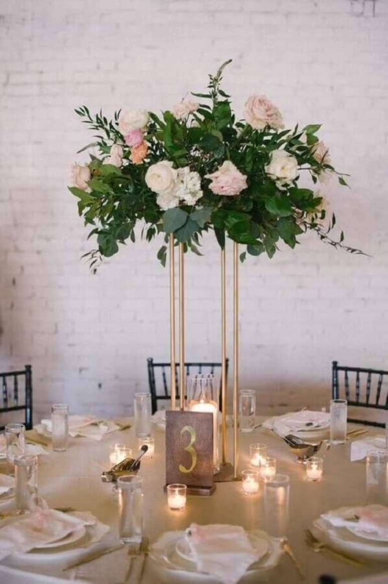 21. Enfeite de mesa para casamento com arranjo de flores sobre suporte dourado – Foto: Pinterest