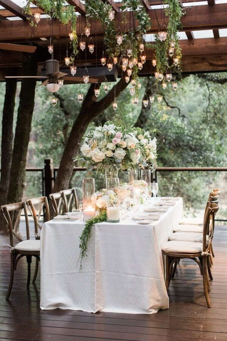 22. Enfeite de mesa para casamento com arranjo de rosas e luminárias pendentes sobre a mesa – Foto: MODwedding