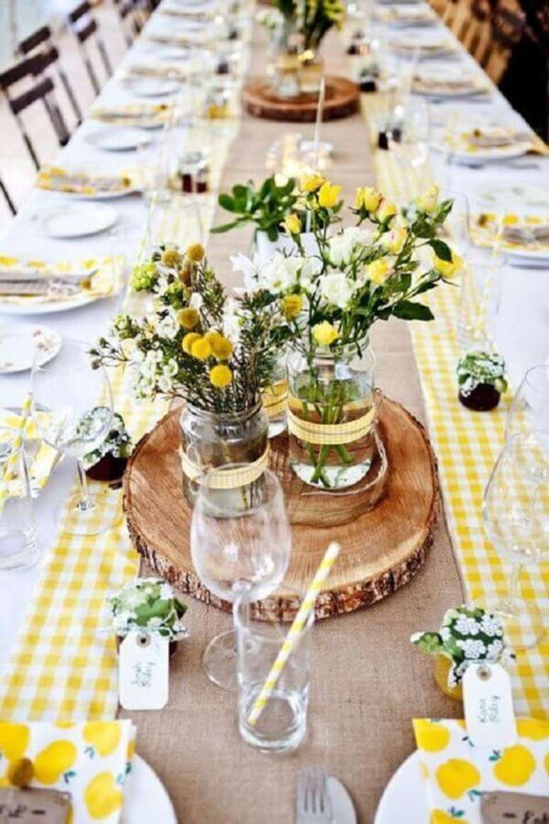 38. Enfeite de mesa para casamento simples com tábuas de madeira e vasinhos de vidro com flores amarelas – Foto: Blog de Boda