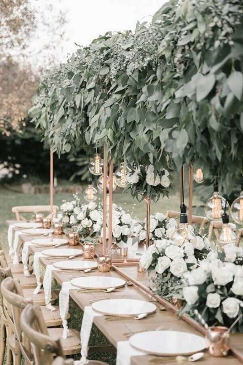 45. Linda decoração com enfeites de casamento para mesa de convidados ao ar livre com muitas folhagens e arranjo de rosas brancas – Foto: Pinterest