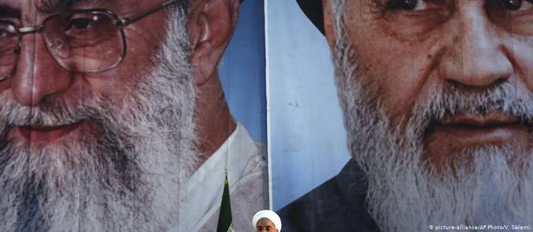 Presidente iraniano Hassan Rohani discursa em frente a retratos enormes dos aiatolás Khamenei (esq.) e Khomeini