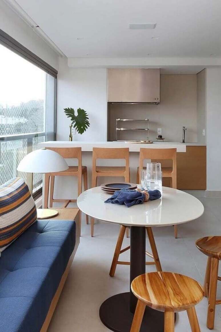 33. Decoração clean para espaço gourmet com banquetas de madeira e mesa redonda branca – Foto: Pinterest