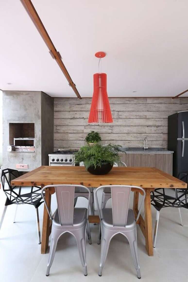 9. Decoração com estilo industrial para área gourmet com mesa de madeira e luminária vermelha – Foto: Antonio Armando de Araujo