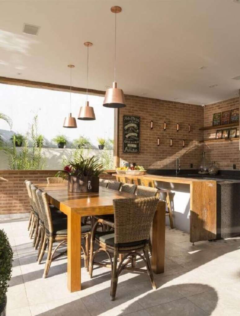 50. Decora&ccedil;&atilde;o r&uacute;stica para espa&ccedil;o gourmet com parede de tijolinho e lumin&aacute;rias sobre mesa de madeira &ndash; Foto: Studio Deux