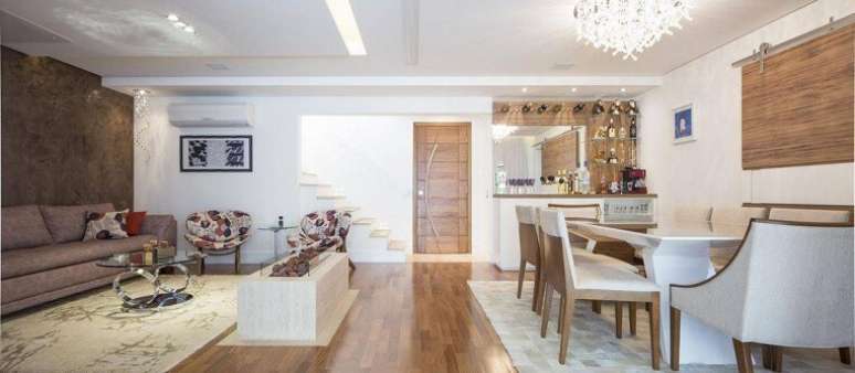 63. O piso de madeira compõe o revestimento tanto da sala de estar quanto da sala de jantar. Projeto por C+H Arquitetura