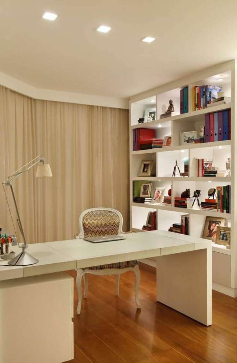 28. Home office com piso de madeira e móveis brancos. Projeto de Vivian Coser