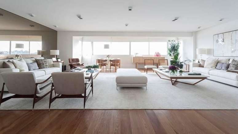 75. Sala de estar ampla com a presença de piso de madeira. Projeto por BMG Arquitetura