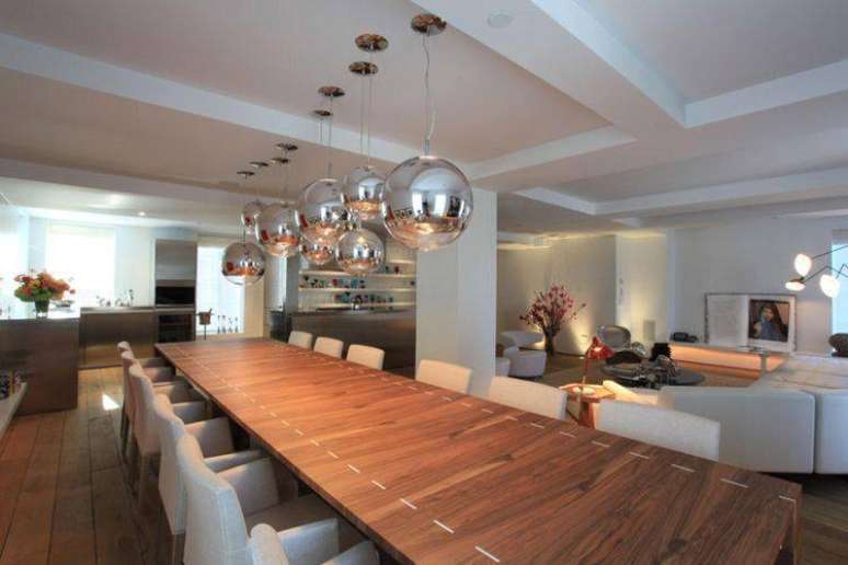 23. Mesa de jantar de madeira basante extensa é perfeita para lugares grandes