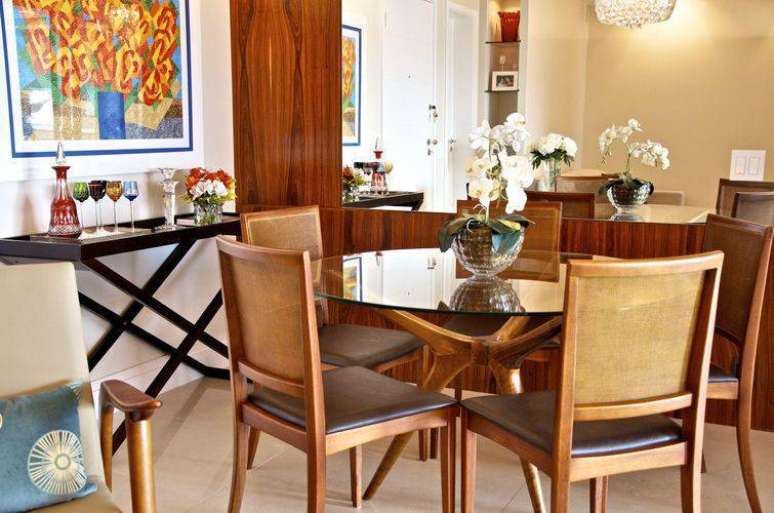 25. A mesa de jantar de vidro com cadeiras de madeira dá um contraste interessante para o cômodo. Projeto de Danyela Correa