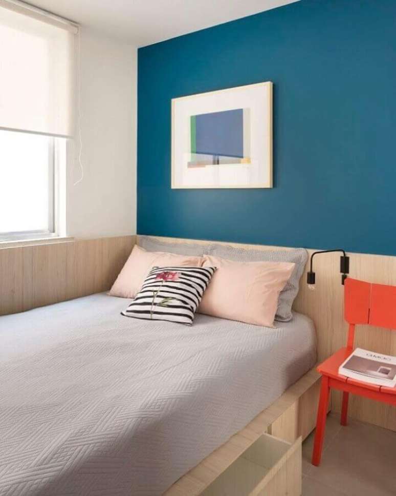 56. Decoração simples para quarto de solteiro com parede azul petróleo e cadeira laranja – Foto: Tripper Arquitetura