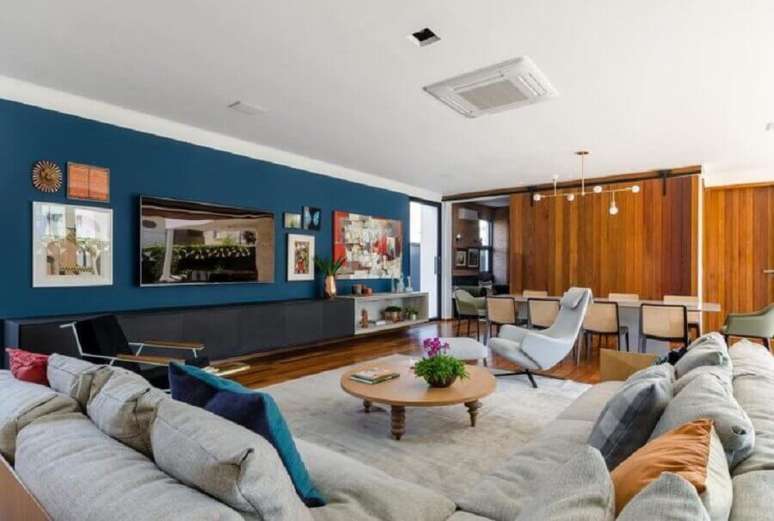 65. Sala ampla decorada com sofá de canto bege e tinta de parede azul petróleo – Foto: Andrea Murao