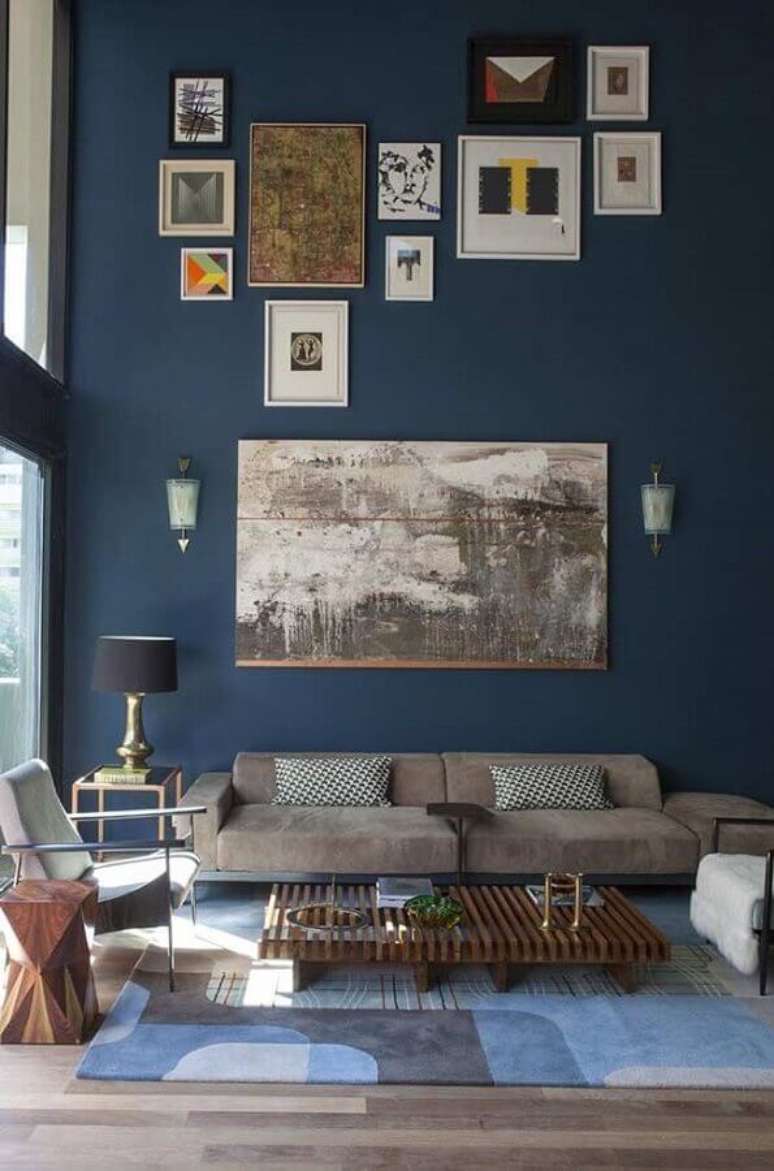 70. Tinta de parede azul petróleo para sala com pé direito e vários quadros – Foto: Pinterest