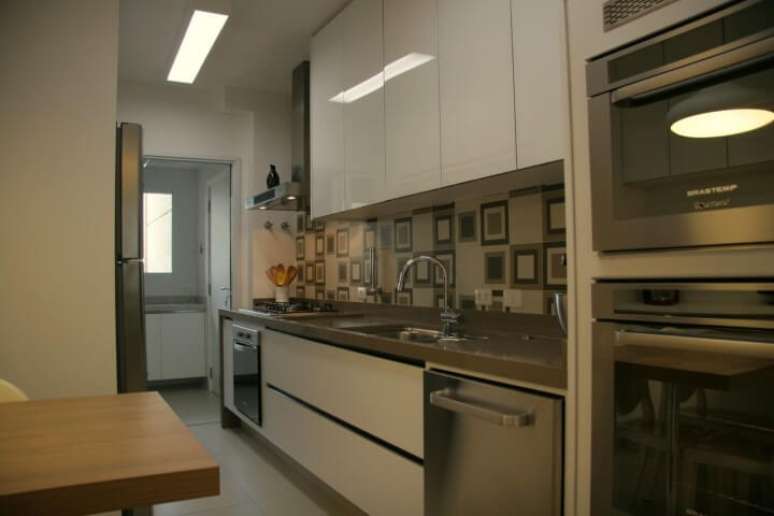 32. Armário de cozinha de parede branco em ambientes integrados. Projeto de Moussi Arquitetura