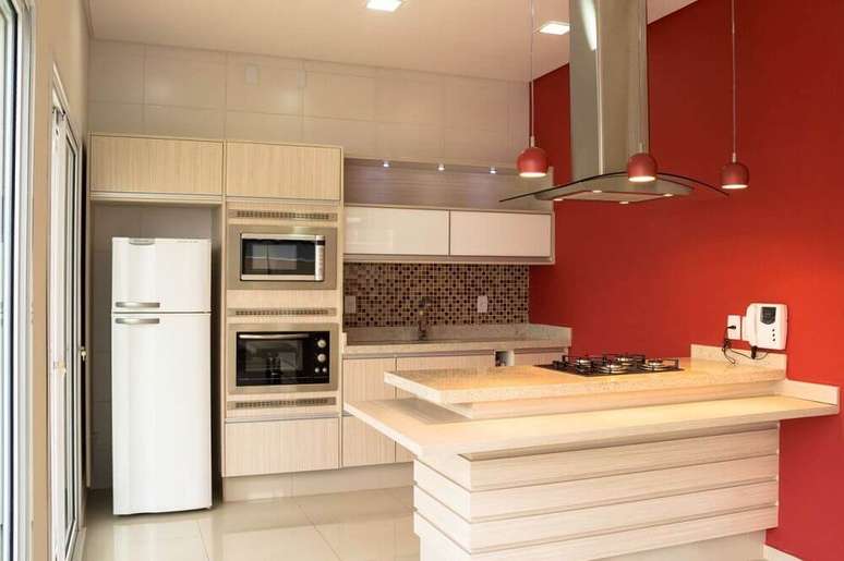 24. Decoração de cozinha com coifa de ilha em vidro e alumínio e com pendentes vermelhos