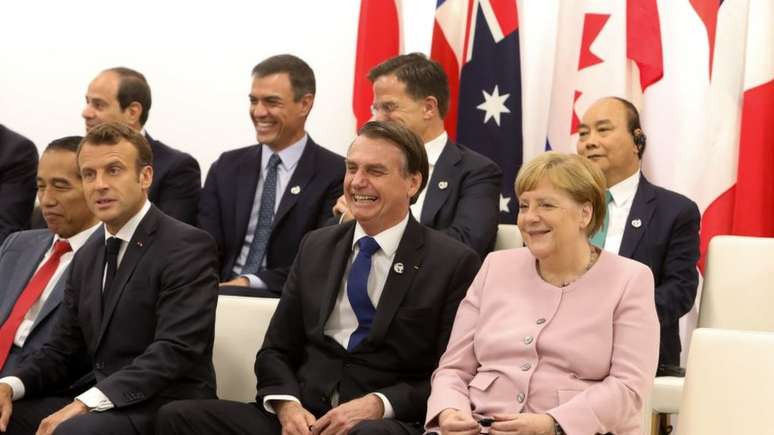 Bolsonaro (centro) com Emmanuel Macron (esq.) e Angela Merkel (dir) no Japão: presidente perderia a aposta a respeito da Amazônia