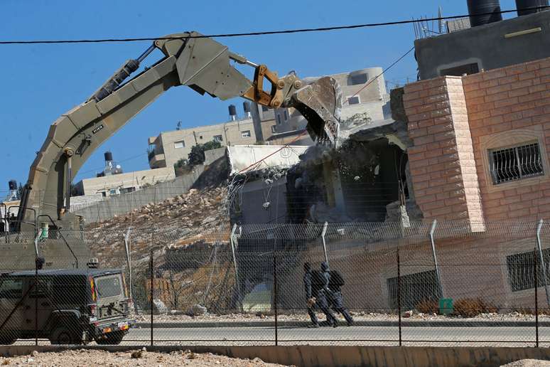 Forças israelenses fazem patrulha enquanto máquinas demolem casa na vila de Sur Baher, na Cisjordânia