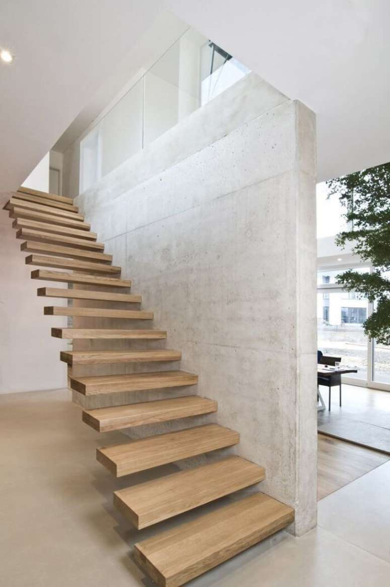 25. Escada flutuante de madeira clara fixada em parede de concreto. Fonte: Pinterest