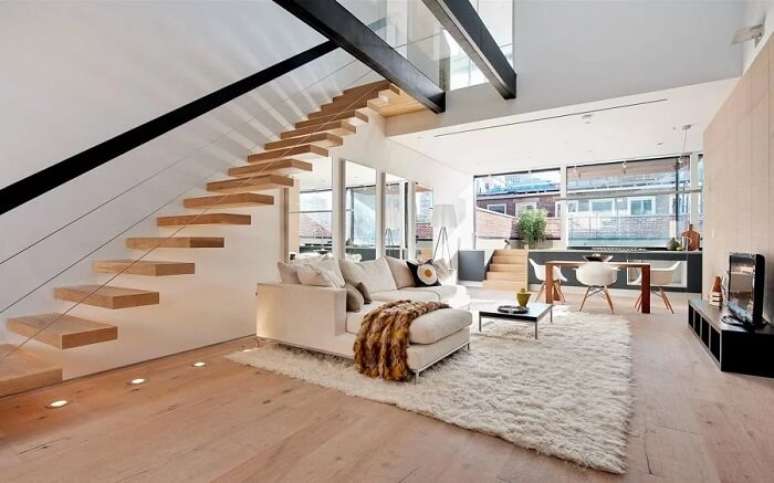 45. Escada flutuante de madeira encanta e complementa a decoração desta sala de estar. Fonte: Habitissimo