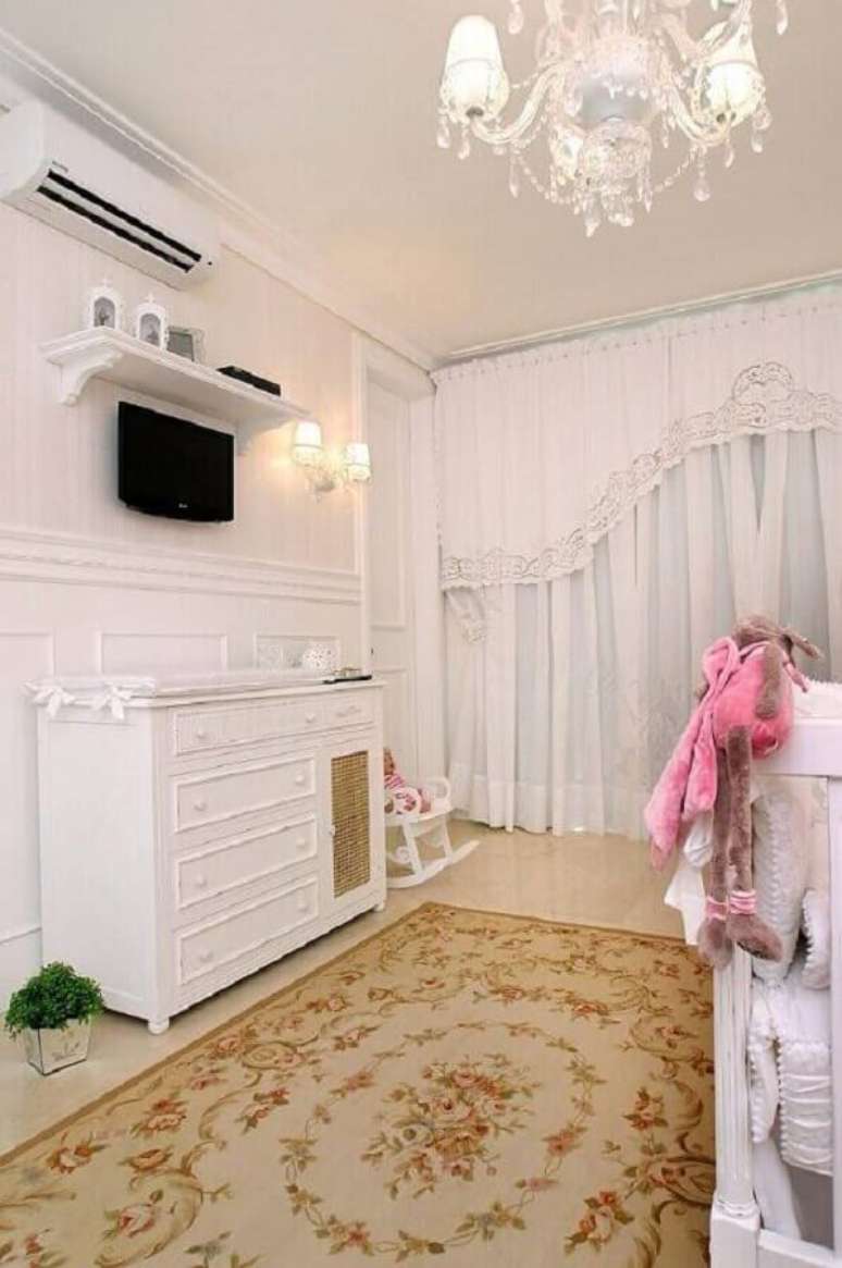 27. Decoração clássica com cômoda branca para quarto de bebê todo branco com lustre e tapete floral – Foto: Nicolle do Vale