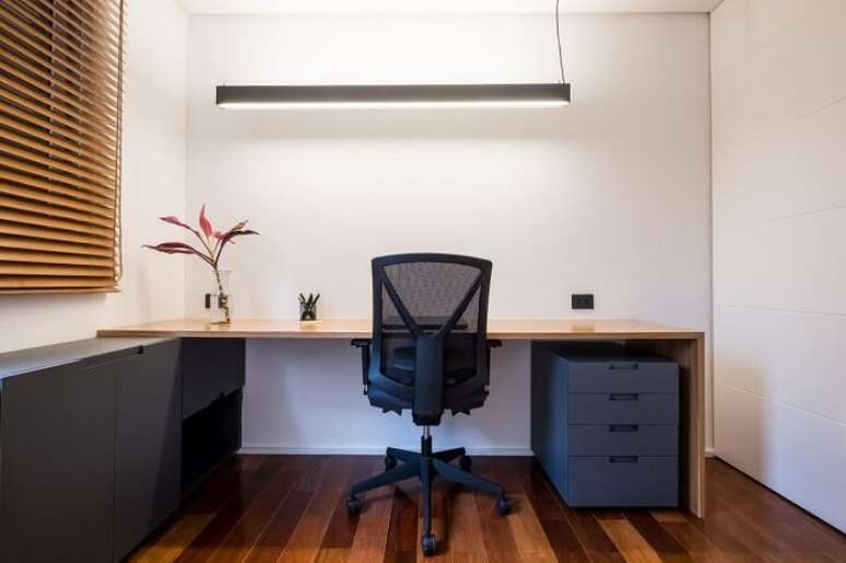 16. Bancada de madeira, luminária metálica e cadeira para escritório com rodízios. Projeto por INÁ Arquitetura