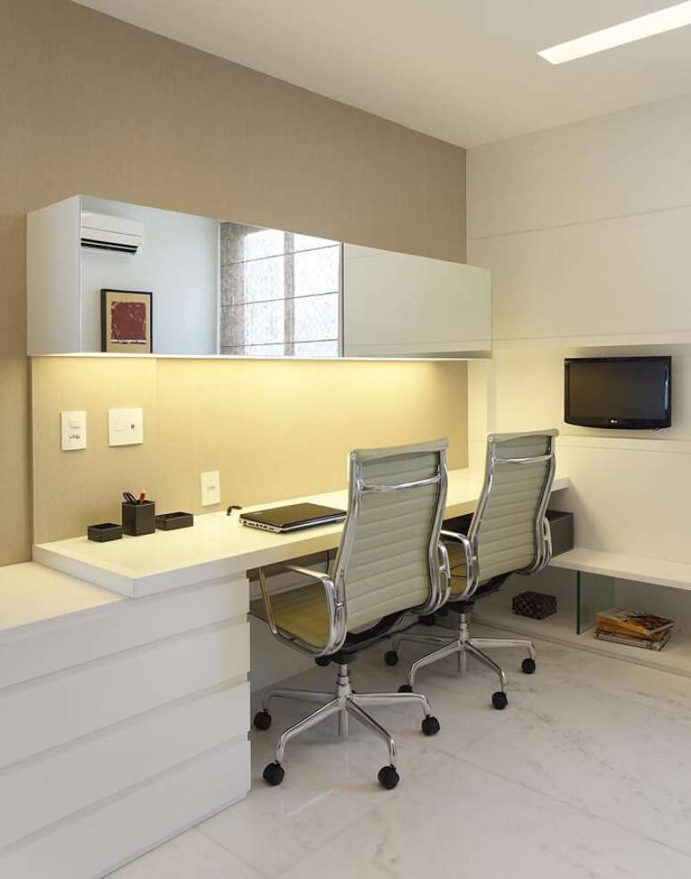 37. Home office com mesa branca e cadeira para escritório com estrutura metálica e rodízios em preto. Projeto por Leila Dionizios