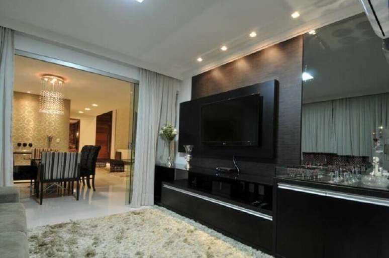 29. Painel com rack preto para sala de estar com tapete felpudo – Foto: Cypriana Pinheiro
