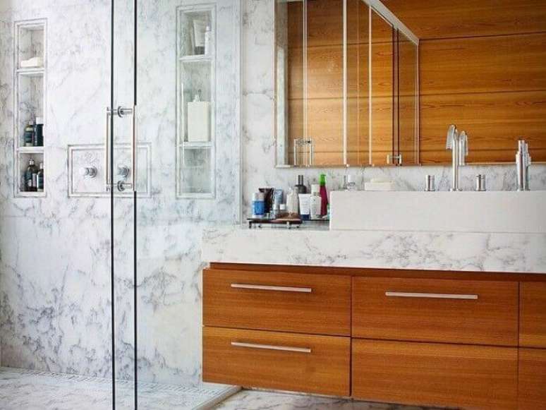 65. Arm&aacute;rio de banheiro feito com estrutura de madeira e bancada de m&aacute;rmore. Fonte: Fernanda Marques