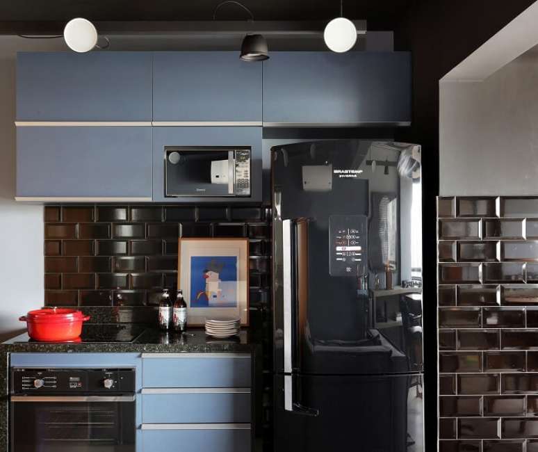 18. Cozinha com decoração formada por armários azul e geladeira preta inverse. Projeto por Concretize