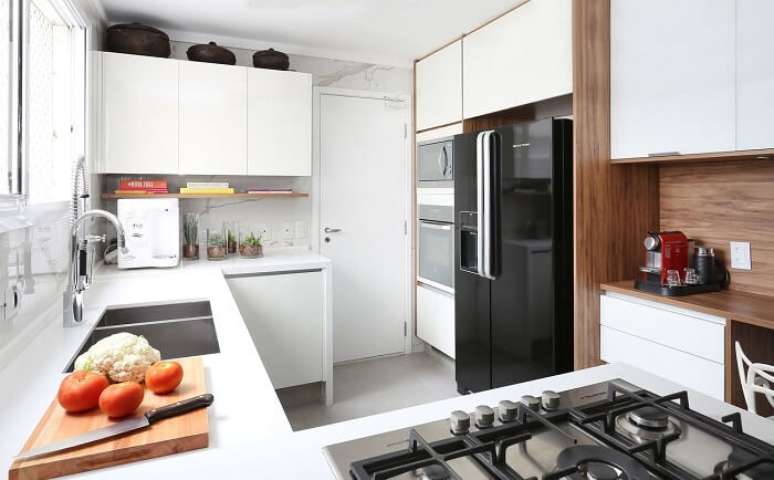 29. Cozinha compacta com armários brancas e geladeira preta side by side embutida. Projeto por Estudio AE