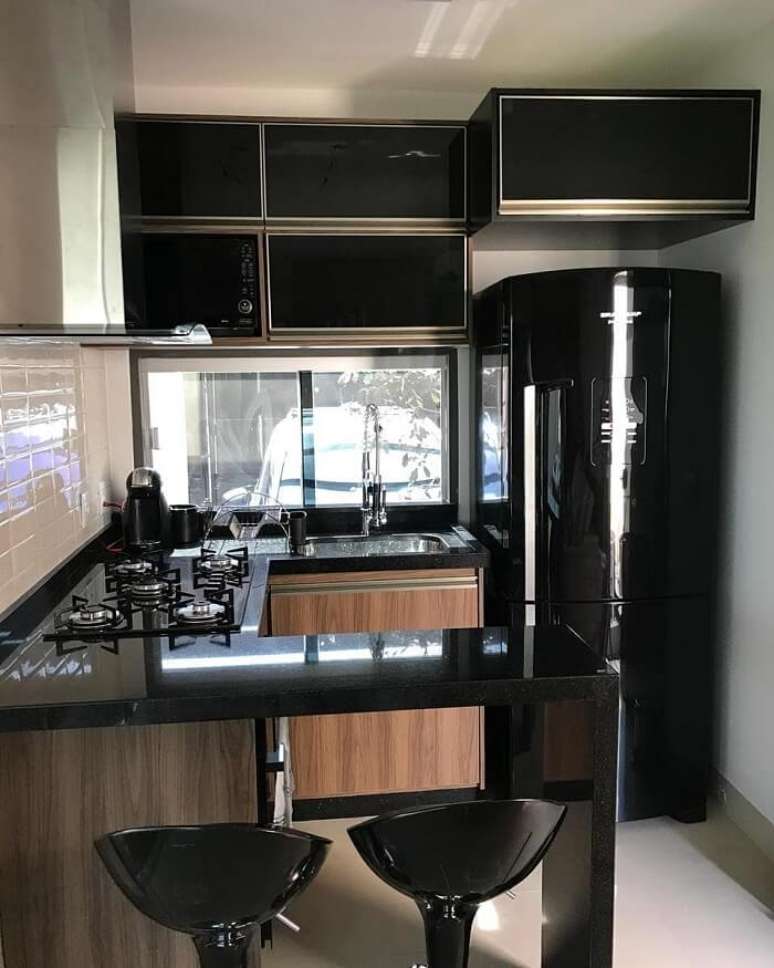 43. Cozinha compacta com cooktop e geladeira preta embutida. Fonte: Tua Casa