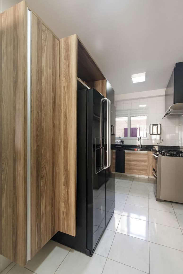 24. Cozinha planejada conta com a presen&ccedil;a de uma geladeira preta. Projeto por Fernanda Duarte