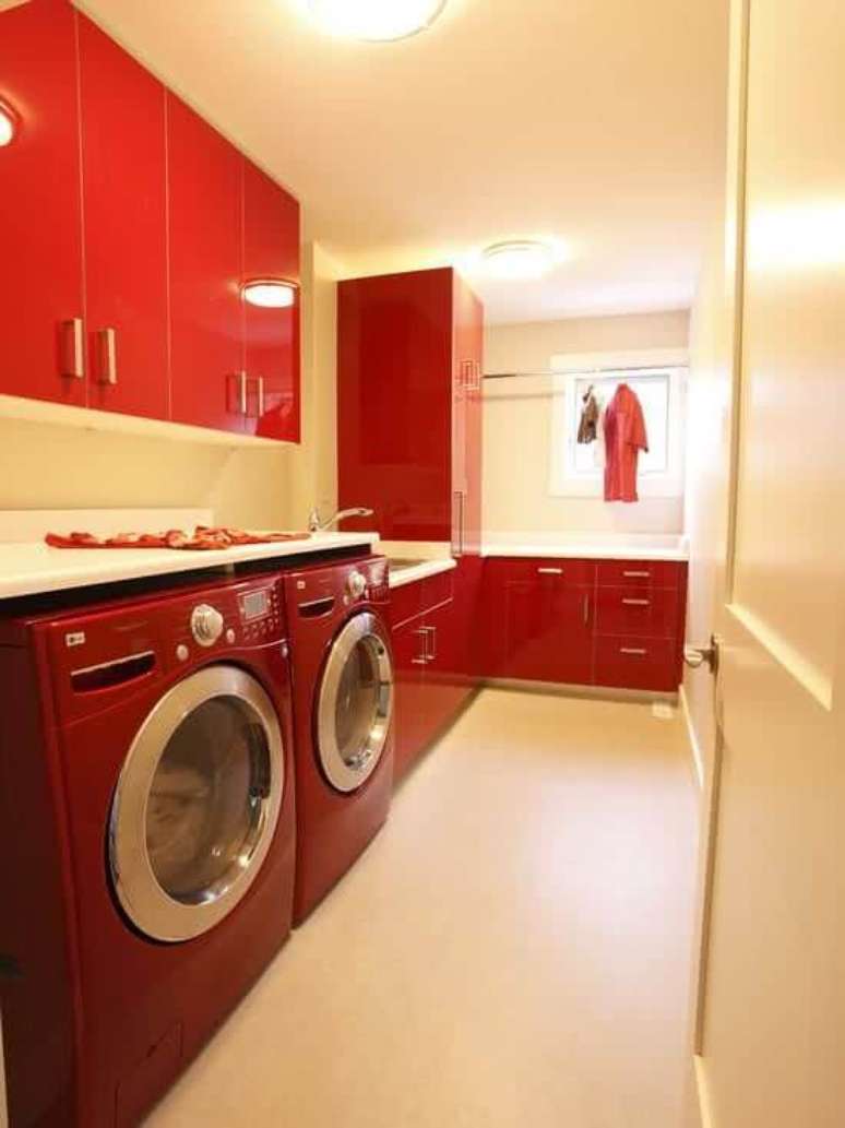 12. Lavadora de roupas vermelha, na mesma cor da lavanderia