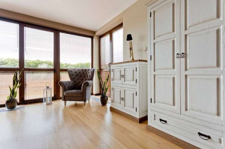 35. A sala de estar com móveis mais antigos ganha a modernidade do carpete de madeira mais clara.