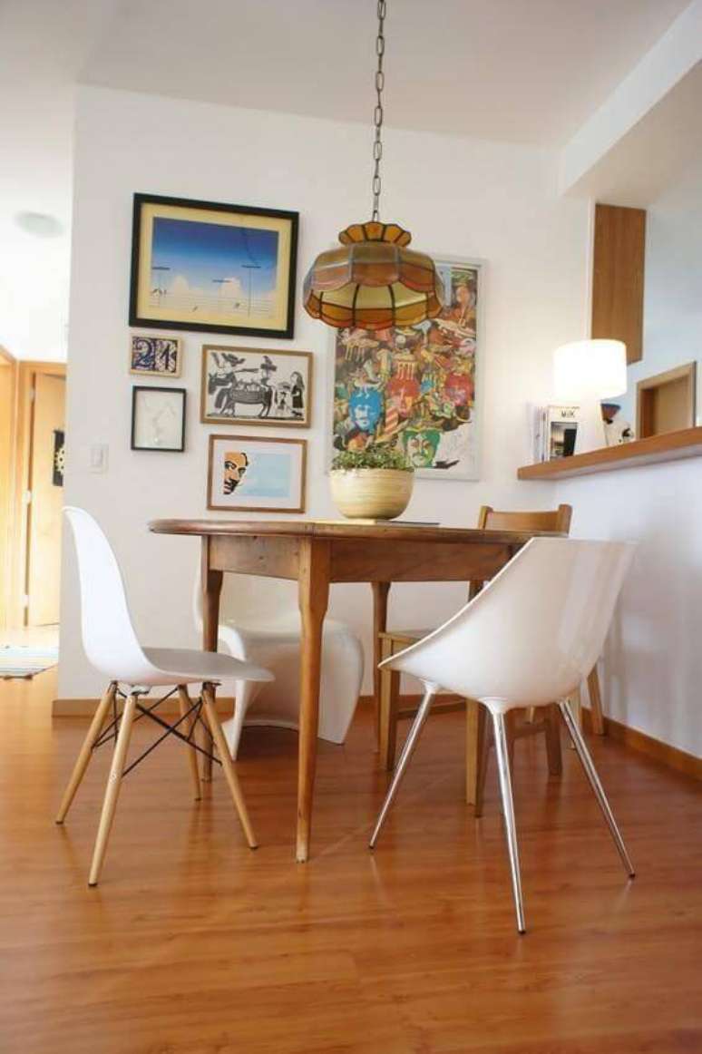 50. A sala de jantar com cadeiras diferentes harmoniza com o chão com carpete de madeira. Projeto por Estudio Ferdi.