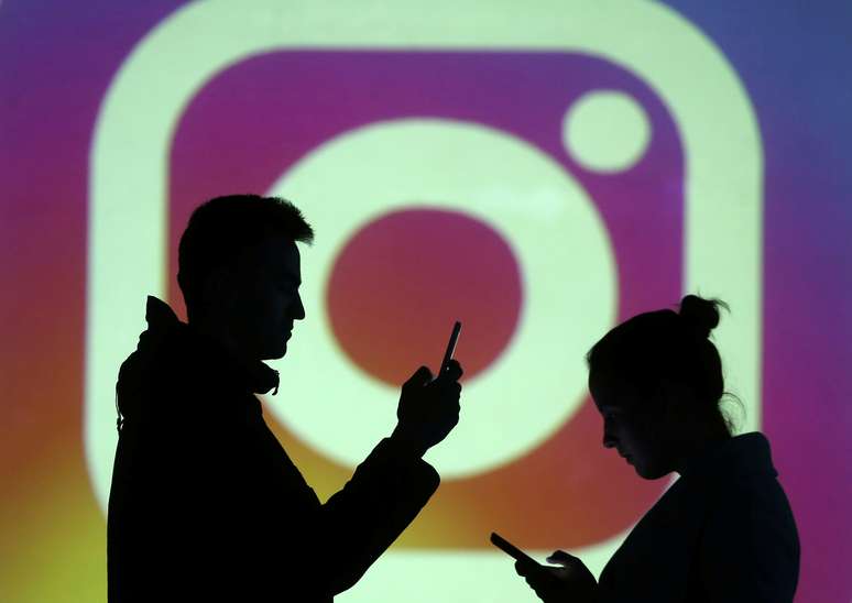 Silhueta de usuários de smartphones à frente de logotipo do Instagram. 28/3/2018.  REUTERS/Dado Ruvic/Illustration 