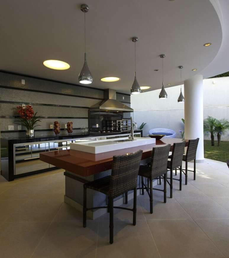 16. Bancada vermelha, pendentes prateados e churrasqueira de vidro com coifa de inox. Projeto por Aquiles Nicolas K&iacute;laris