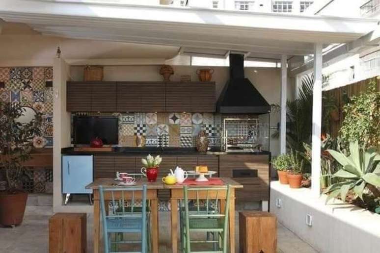 45. &Aacute;rea de lazer pequena com m&oacute;veis em madeira e churrasqueira de vidro. Fonte: Terra