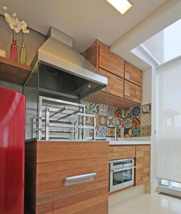 33. Varanda gourmet com ladrilho na pia e churrasqueira de vidro com coifa de inox. Projeto por Officina 44