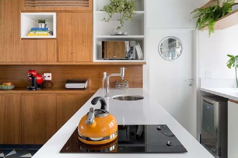19. Bancada de cozinha feita em silestone branco com armário de madeira e cooktop – Foto: Tria Arquitetura