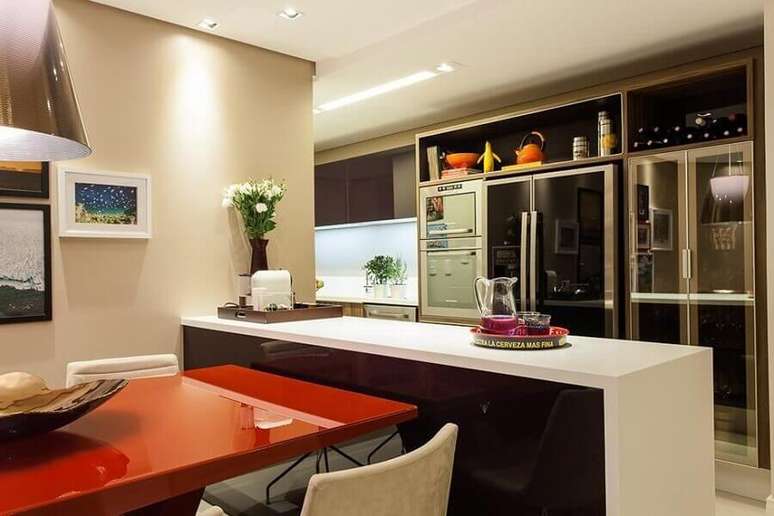 38. Cozinha americana decorada com armários planejados e mesa vermelha acoplada na bancada para cozinha – Foto: Decor Salteado