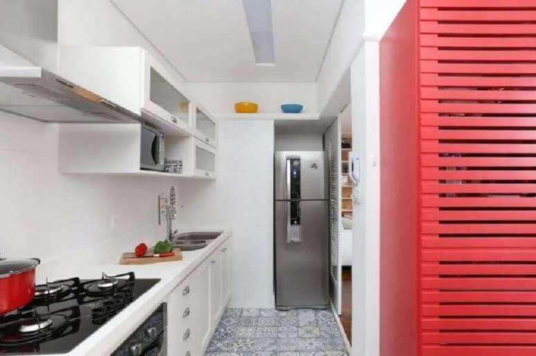 42. A bancada para cozinha totalmente branca destaca o piso de azulejos desenhados e o móvel vermelho – Foto: Achduo Arquitetura