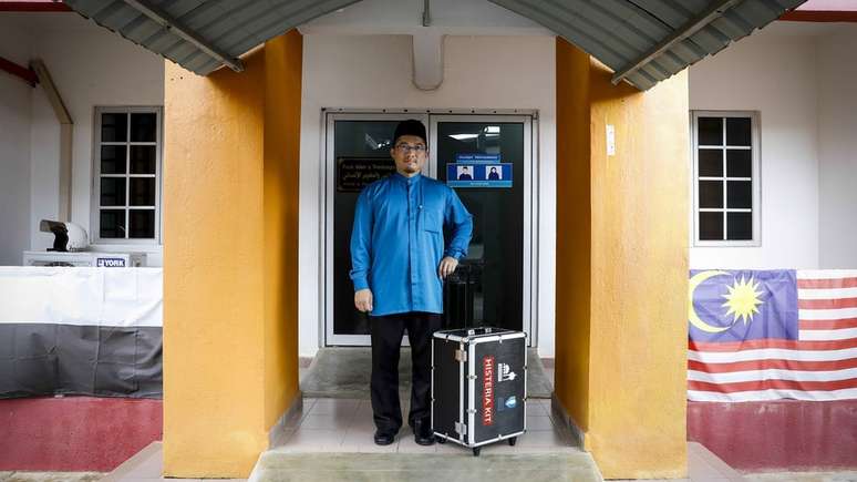 Mahyuddin Ismail posa com seu kit "anti-histeria" do lado de fora de sua clínica na Universidade de Pahang
