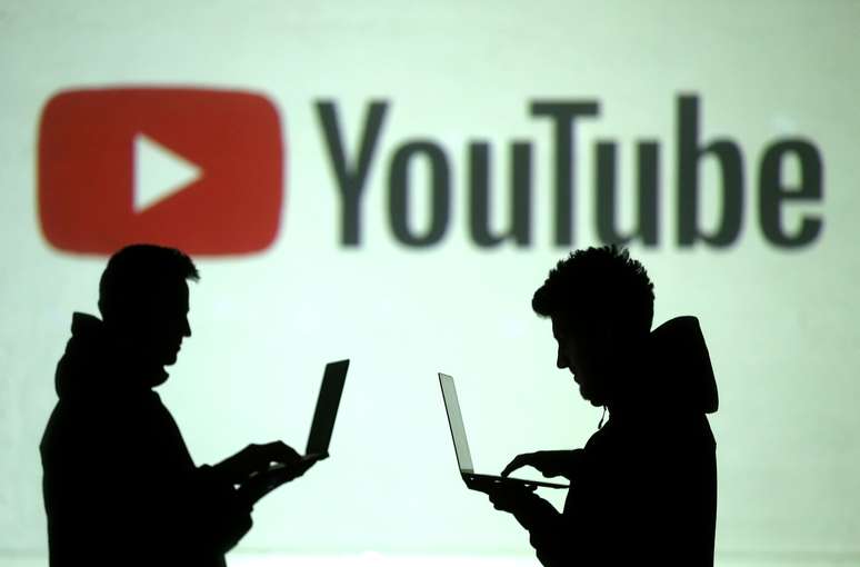 Silhueta de usuários de dispositivos móveis são vistos à frente de um logotipo do YouTube.  28/3/2018.  REUTERS/Dado Ruvic