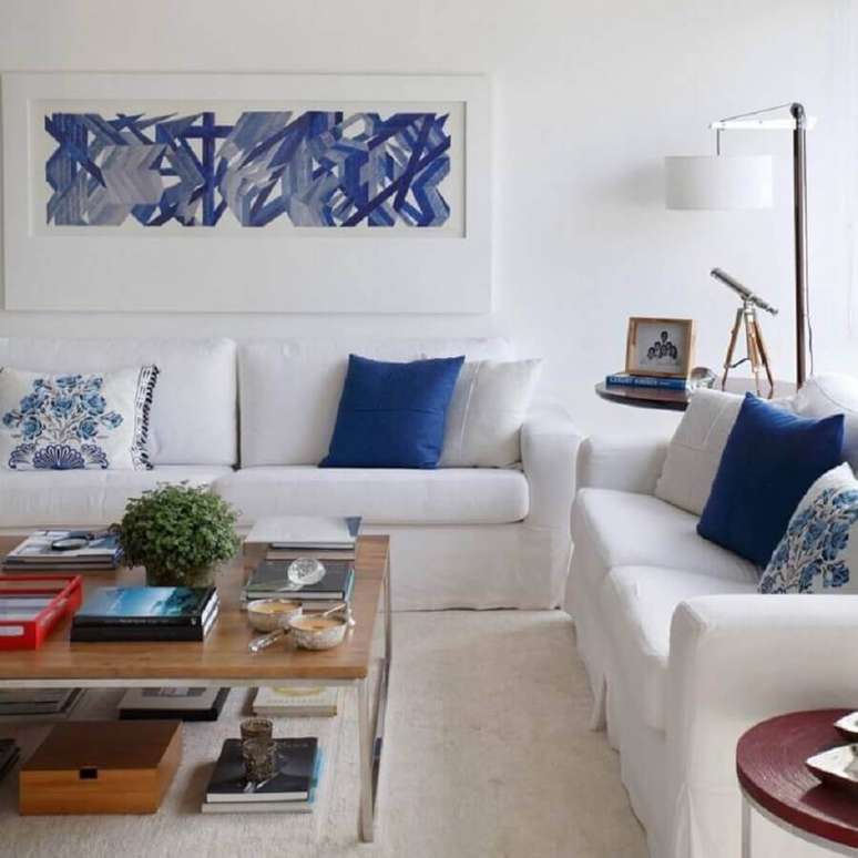 15. A decoração com sofá branco e almofadas azuis garante a sala um toque suave na decoração – Foto: Adriana Vale Patricia Carvalho