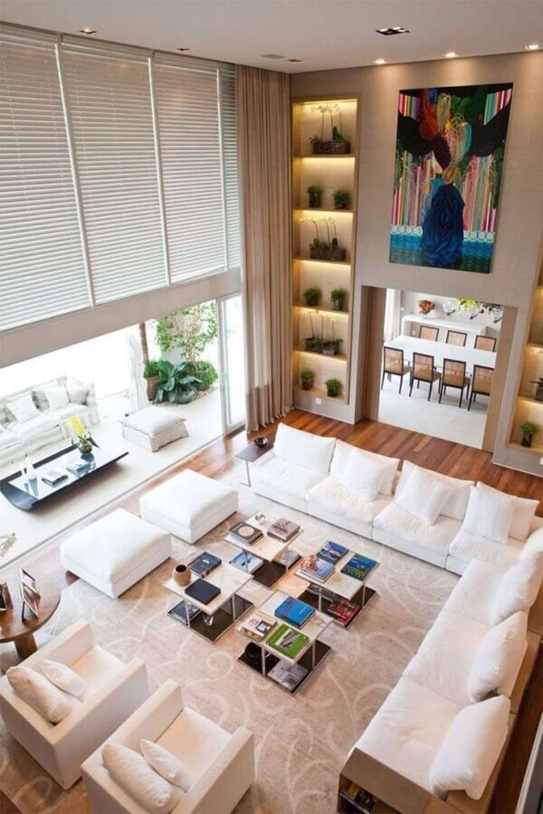 1. Decoração em tons neutros para sala ampla com sofá de canto branco combinando com as poltronas e puffs – Foto: Pinterest